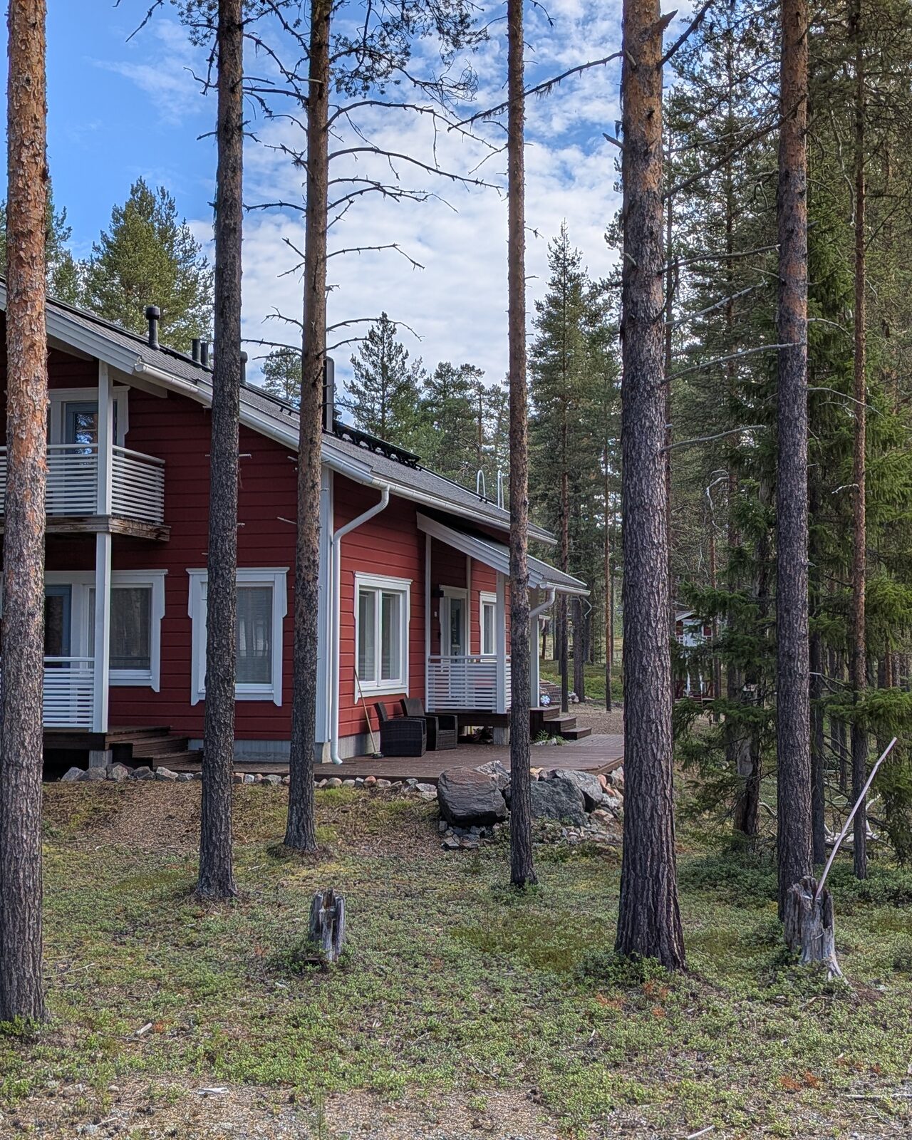 Das rote Holzhaus mit Terrasse, umgeben von Kiefernwald in Lappland